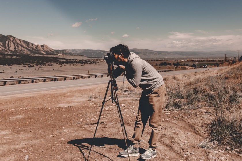 A photographer with a camera on a tripod on the road | Skylum Blog