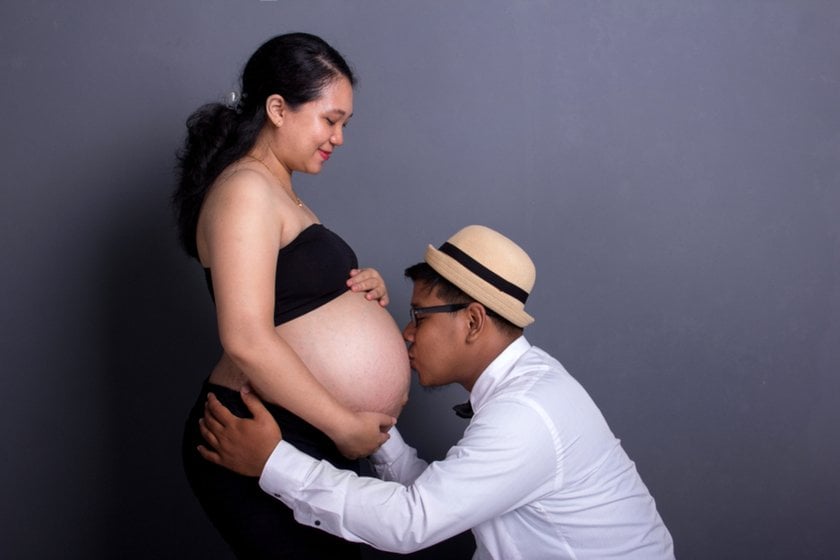 A man in a hat kisses his pregnant wife's belly | Skylum Blog