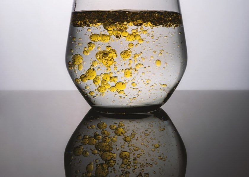 A glass of water with drops of oil in it | Skylum Blog