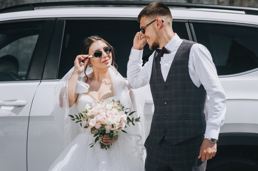 Newlyweds wearing glasses near a car | Aperty Blog