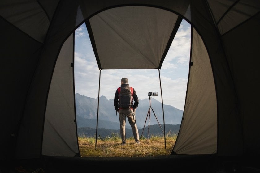 Photographer in mountains with tripod camera and tent | Skylum Blog