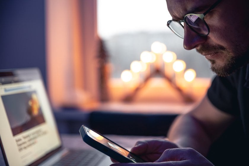 Uomo con telefono e laptop | Skylum Blog