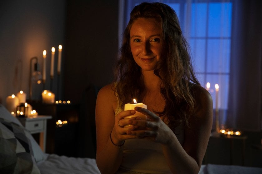 A girl in a room with candles holds a candle in her hands | Skylum Blog