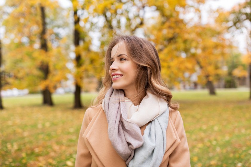 A girl in a scarf in an autumn park looks into the distance | Skylum Blog