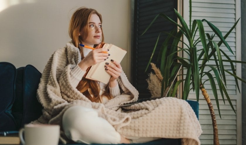 A girl in a blanket takes notes in a notebook | Skylum Blog