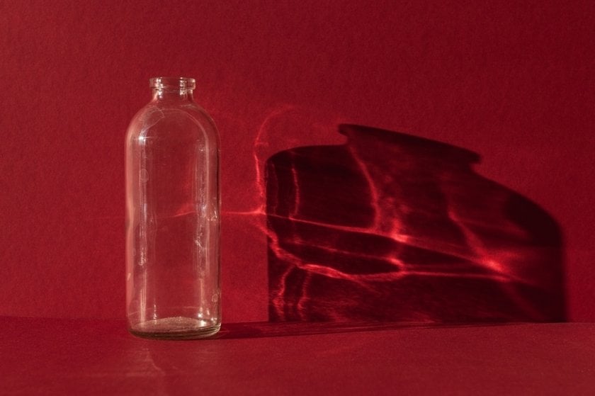 Glass bottle on a red background with reflection | Skylum Blog