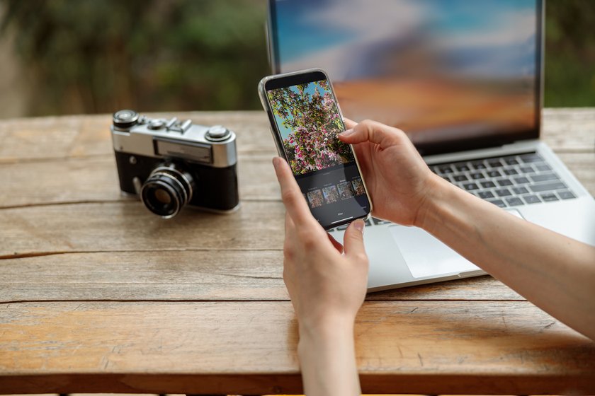 A phone with a photo editor in hand a camera and a laptop nearby | Skylum Blog