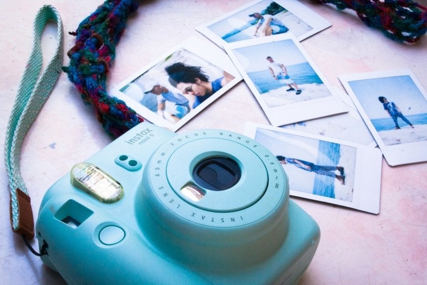 A blue Instax on a table with photos | Skylum Blog