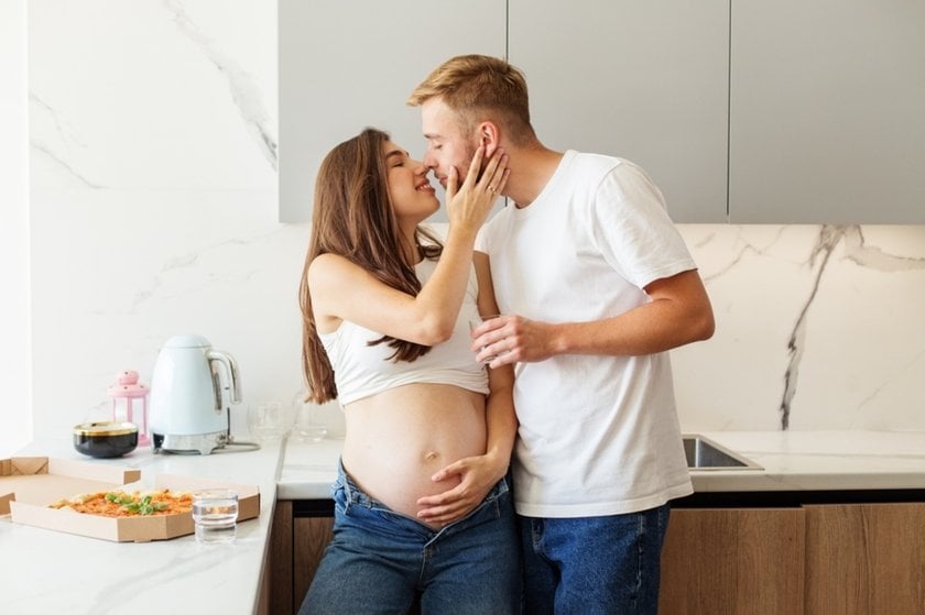 A man and his pregnant woman kiss in the kitchen | Skylum Blog