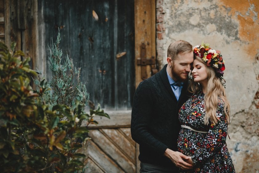 A pregnant girl with a wreath on her head hugs her husband | Skylum Blog