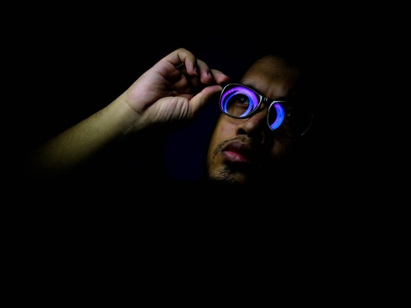 Portrait of a guy wearing glasses in a dark studio | Skylum Blog