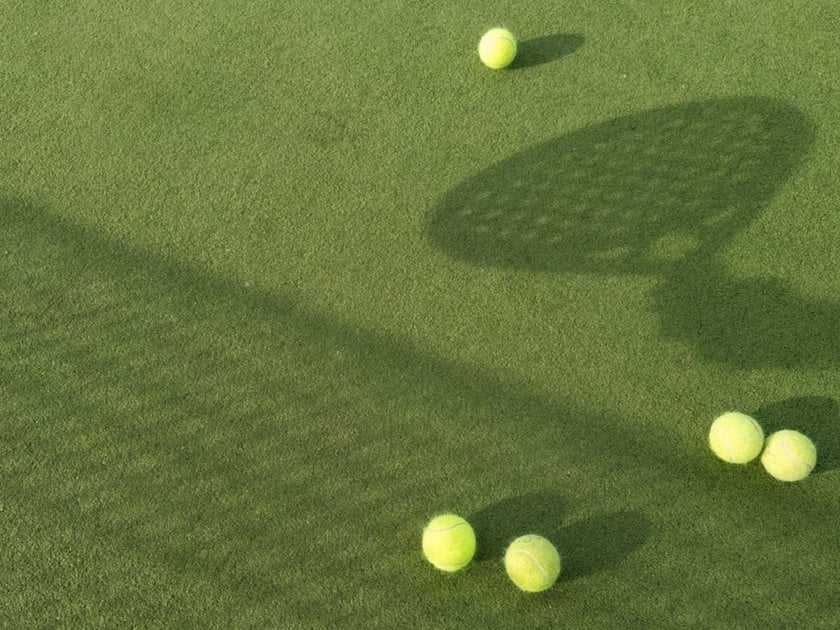 Shadow of a net and racket on grass with tennis balls | Skylum Blog