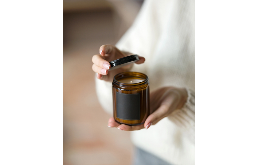 A candle in a glass jar in hands | Skylum Blog