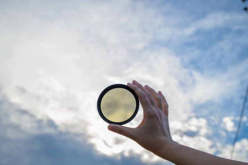 Photo of a photographer holding a filter against the sky | Skylum Blog