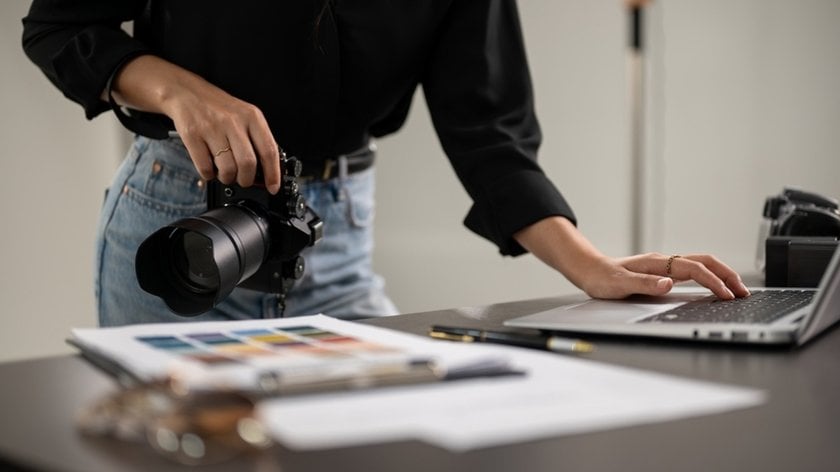 A photographer at a laptop with a camera in his hands | Skylum Blog