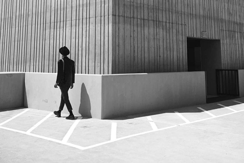 A black and white photo of a guy walking along a building | Skylum Blog