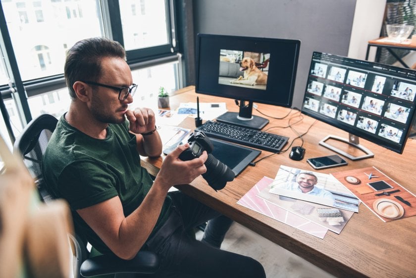 Photographer in front of computers with a camera | Skylum Blog