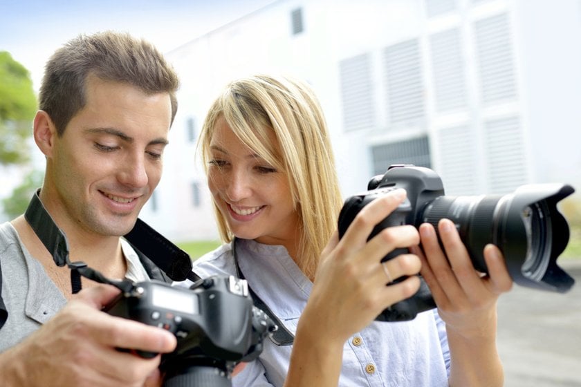 Two photographers looking at a camera | Skylum Blog