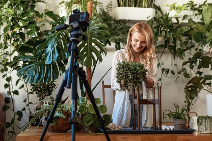 Photographer adjusting camera settings for botanical photography in garden environment