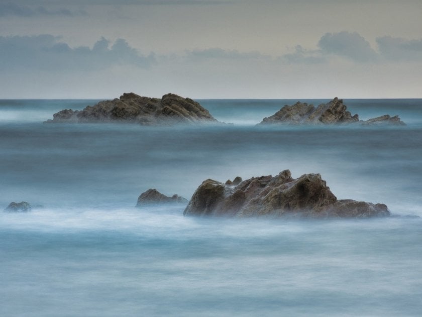A long-exposure photo of the ocean with rocks | Skylum Blog