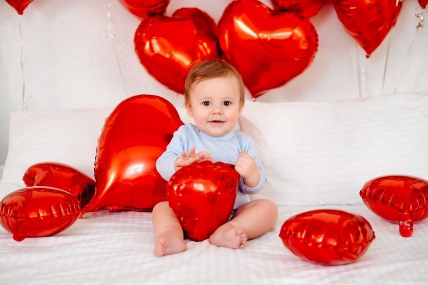 Baby on a bed with heart-shaped balloons | Skylum Blog