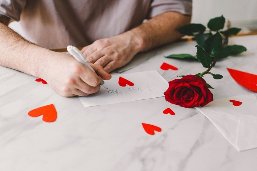 Hands cutting out paper hearts near a red rose | Skylum Blog