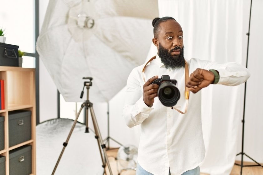 A photographer with a camera looks at his watch in surprise | Skylum Blog